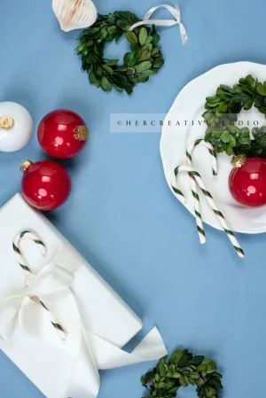 Red Ornaments & Holiday Gift With Candy Canes on Sky Blue Background